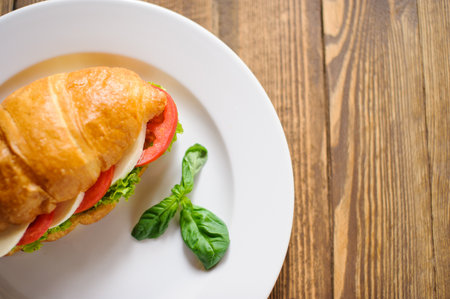 Fresh croissant with ham and salad leaf on dark wooden backgroundの写真素材