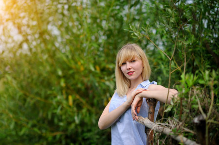 Young charming woman in jeans lies in green summer park.の写真素材