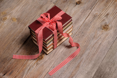 Books wrapped with color ribbon, on wooden tableの写真素材