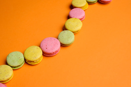 Sweet and colourful french macaroons or macaron on orange background