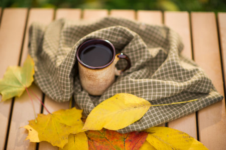 Autumn leafs and coffee cup on wooden table.