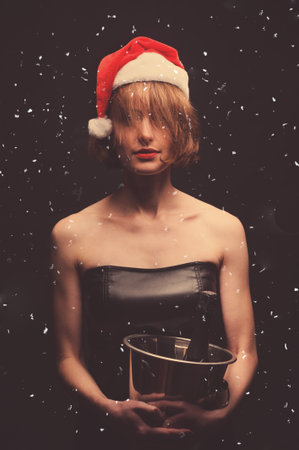 Christmas gifts. Model girl in santa hat. Girl holding champagne and glasses, isolated on black background. New Year holidays.の写真素材