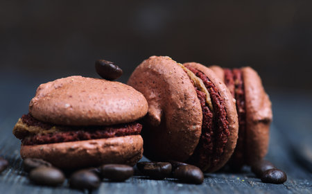 Sweet and colourful french macaroons with coffee beans on the wooden backgroundの写真素材