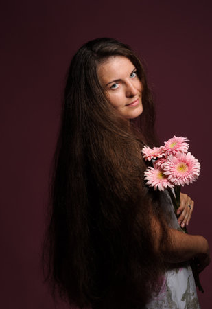 smiling woman with pink flowers. Studio pink backgroundの写真素材