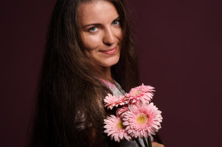 smiling woman with pink flowers. Studio pink backgroundの写真素材