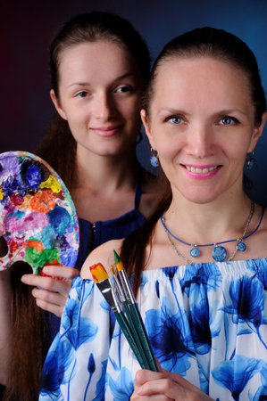 two artists with paints and brushes in hands over black backgroundの写真素材