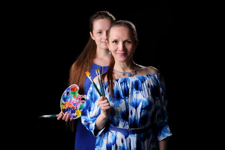 two artists with paints and brushes in hands over black backgroundの写真素材