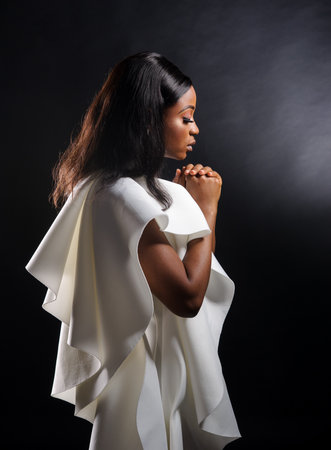 Portrait of a beautiful young African woman in white dress over black background. Studio pictureの写真素材
