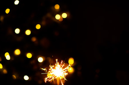 christmas sparklers over dark background with yellow gold lights