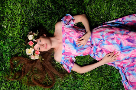 young woman in wreath from folwers on a green grassの写真素材