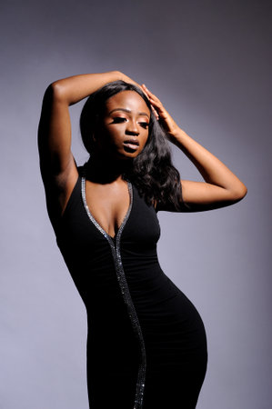 Portrait of a beautiful young African woman in white dress over grey background. Studio pictureの写真素材