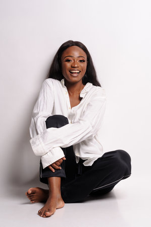 Portrait of a beautiful young African woman in white dress over grey background. Studio pictureの写真素材