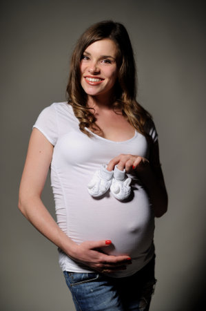 Young beautiful pregnant dressaed in white t-shirt and jeansの写真素材