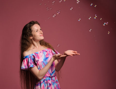 portrait of pretty woman in pink dress over grey backgroundの写真素材