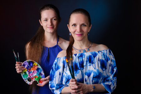 two artists with paints and brushes in hands over black backgroundの写真素材