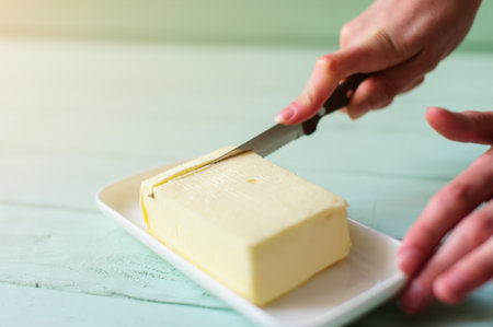 woman hands cutting butter on a lime wooden deskの写真素材