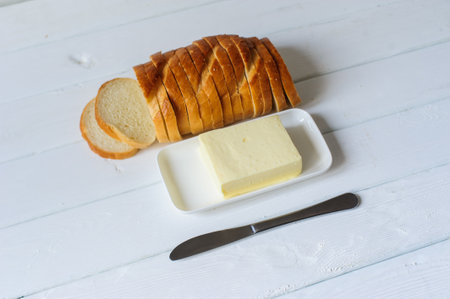piece of butter with knife and bread on a wooden deskの写真素材