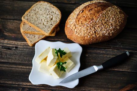 piece of butter with knife and bread on a wooden deskの写真素材