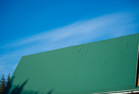 green metal tiles roof over the blue skyの写真素材