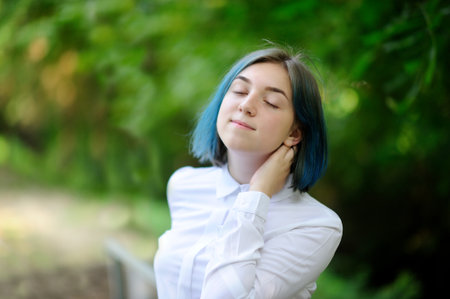 teenage girl in white blouse in green summer parkの写真素材