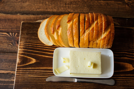 piece of butter with knife and bread on a wooden deskの写真素材