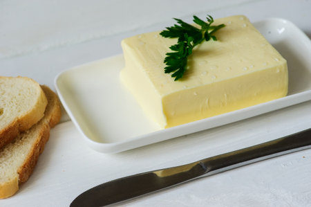 piece of butter with parsley on a white wooden deskの写真素材