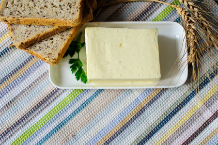 piece of butter with knife, bread and parsley on a wooden deskの写真素材
