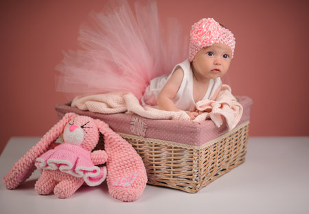 Newborn baby in a basket on pink backgroundの写真素材