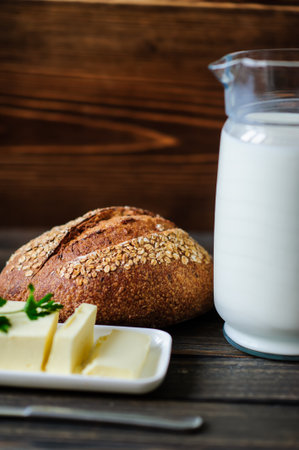 traditional bread loaf with jug of milk on a wooden boardの写真素材