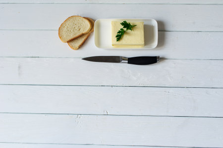 piece of butter with parsley on a white wooden deskの写真素材