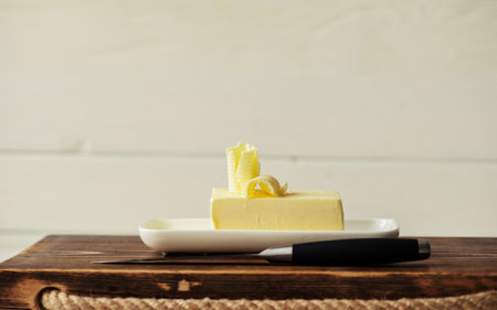 piece of butter with knife on a wooden deskの写真素材