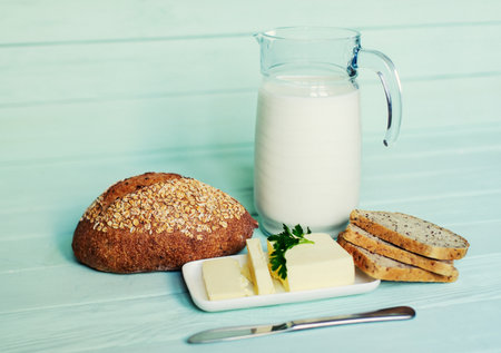 traditional bread loaf with jug of milk on a lime wooden boardの写真素材