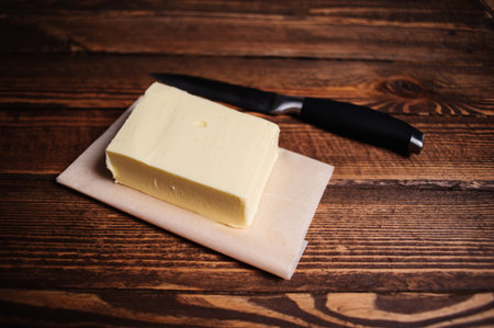 piece of butter with knife on a wooden deskの写真素材