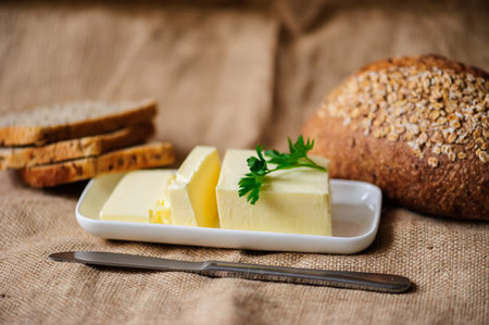 piece of butter with parsley on a sacking textile materialの写真素材