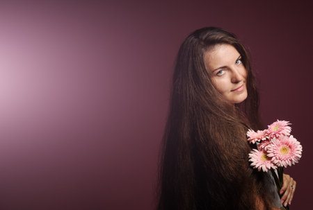 smiling woman with pink flowers. Studio pink backgroundの写真素材