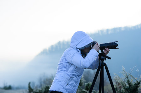 photographer with camera and tripod outdoor making landscape pictureの写真素材