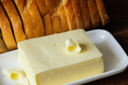 piece of butter with knife and bread on a wooden desk