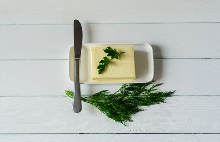 piece of butter with parsley on a white wooden deskの写真素材