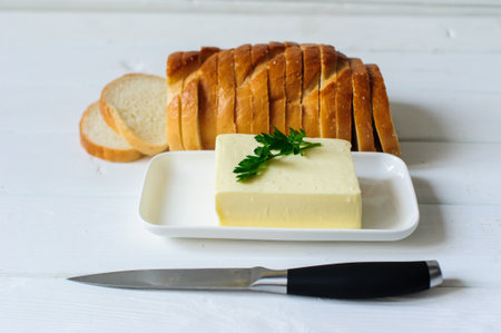 piece of butter with parsley on a white wooden deskの写真素材