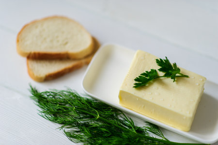piece of butter with parsley on a white wooden deskの写真素材