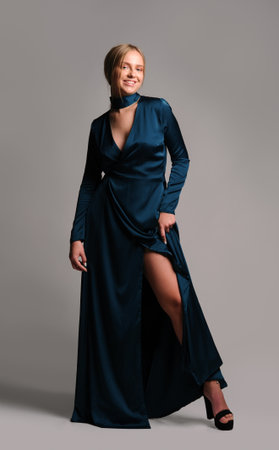 Pretty girl in dark blue dress. Studio picture, grey backgroundの写真素材