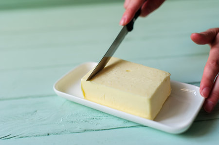 woman hands cutting butter on a lime wooden deskの写真素材