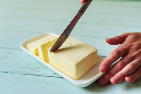 woman hands cutting butter on a lime wooden deskの写真素材