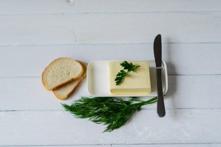 piece of butter with parsley on a white wooden deskの写真素材