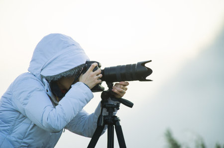 photographer with camera and tripod outdoor making landscape pictureの写真素材
