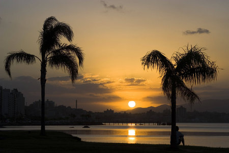 A young man contemplating the sunset on a tropical beach. Florianopolis - Santa Catarina - Brazil.の写真素材