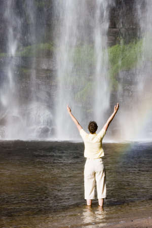 Woman standing in front of a tropical waterfallの写真素材