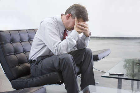 Tired businessman sitting on a chair in a loungeの写真素材