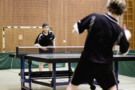 Two persons playing table tennis. Focus on the net of the table.の写真素材