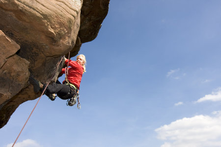 Young smiling woman climbing a sandstone rockの写真素材